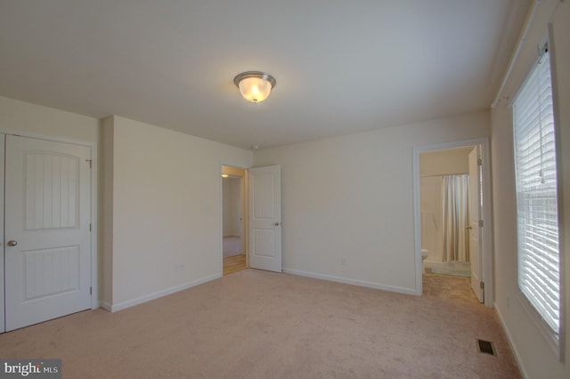 unfurnished bedroom with carpet, visible vents, ensuite bathroom, and baseboards