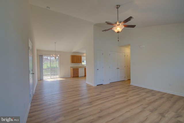 unfurnished living room featuring ceiling fan with notable chandelier, high vaulted ceiling, light wood-style flooring, and baseboards
