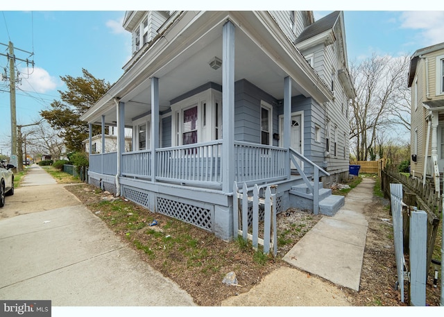 view of property exterior featuring covered porch and fence