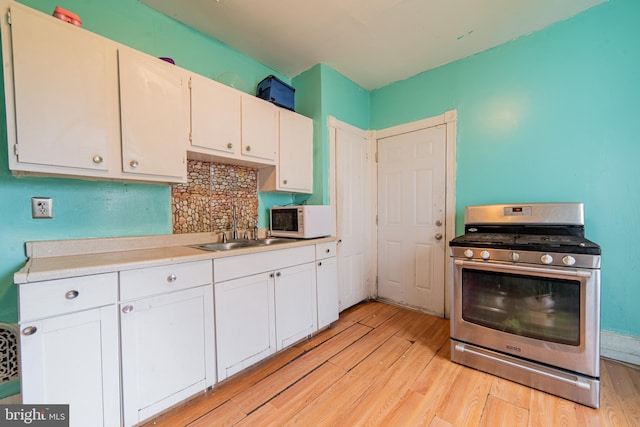kitchen featuring white microwave, light wood-style floors, a sink, and gas stove