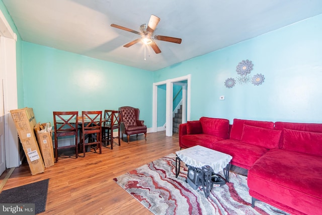 living room featuring ceiling fan, wood finished floors, and stairs