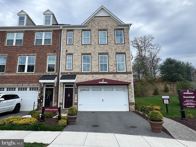 view of property featuring aphalt driveway, brick siding, and a garage