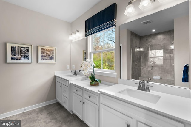 full bathroom with a sink, double vanity, tiled shower, baseboards, and visible vents
