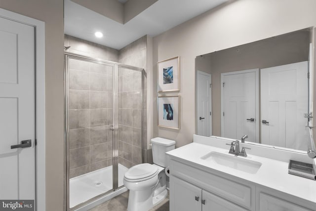 bathroom with vanity, a shower stall, and toilet