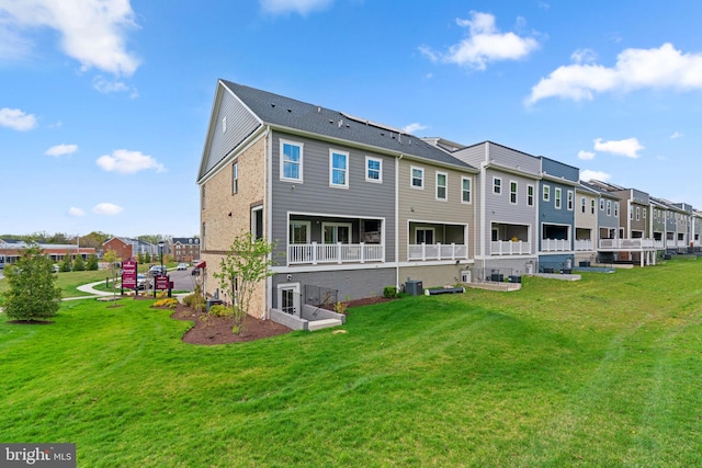 back of house with a lawn, central air condition unit, and a residential view