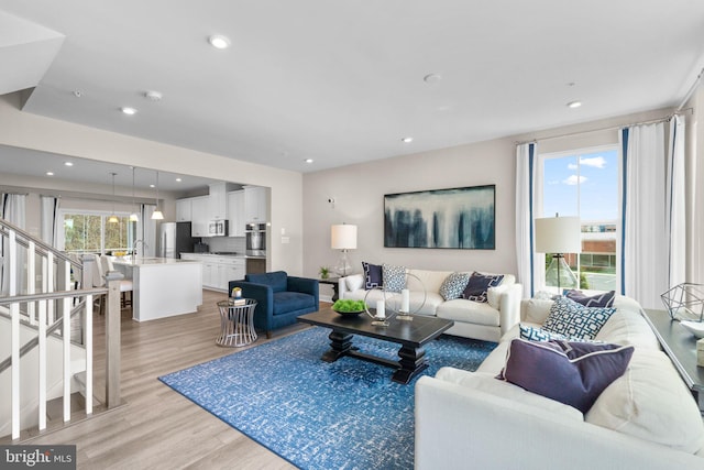 living area with light wood finished floors, recessed lighting, and stairs