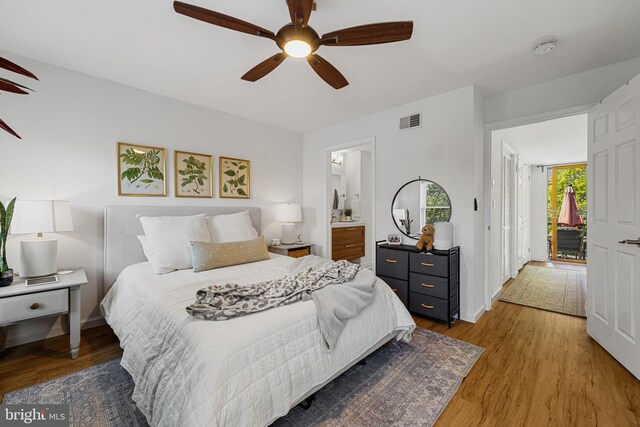 bedroom featuring wood finished floors, baseboards, a ceiling fan, and ensuite bath