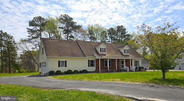 cape cod home with a porch, an attached garage, driveway, and a front yard