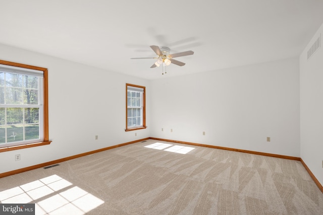 unfurnished room with visible vents, baseboards, ceiling fan, and light colored carpet