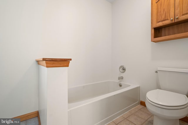 full bathroom with toilet, a tub to relax in, and baseboards
