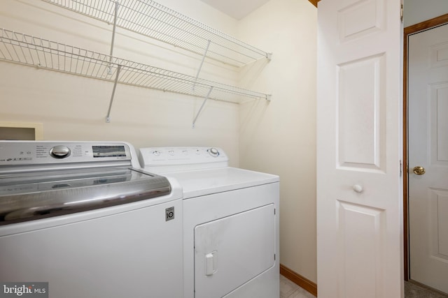 clothes washing area with baseboards and washer and clothes dryer
