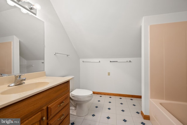 bathroom featuring baseboards, vaulted ceiling, toilet, and vanity