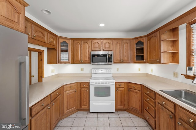 kitchen featuring brown cabinets, white electric stove, a sink, stainless steel microwave, and refrigerator