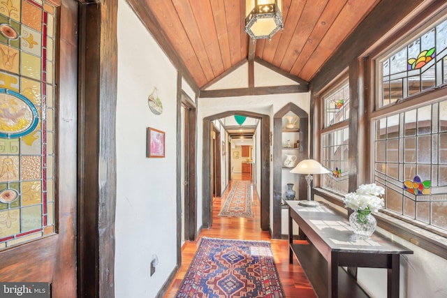 hallway with lofted ceiling, wood finished floors, arched walkways, and wood ceiling