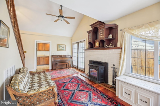 living room with wood finished floors, a wealth of natural light, a ceiling fan, and high vaulted ceiling