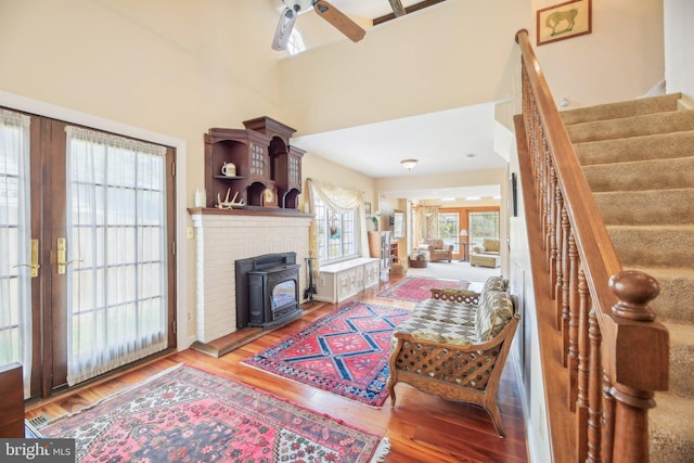 living room featuring french doors, a ceiling fan, wood finished floors, stairs, and a wood stove