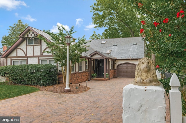 english style home featuring stucco siding, an attached garage, and decorative driveway