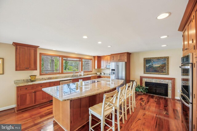 kitchen featuring a premium fireplace, light stone counters, stainless steel appliances, and a sink