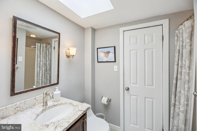 full bathroom with a skylight, vanity, and toilet