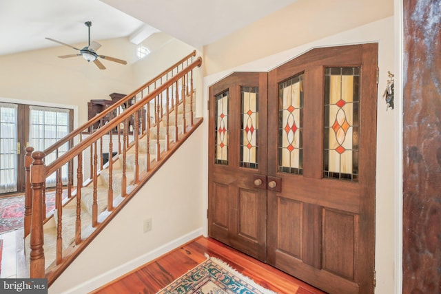 foyer with vaulted ceiling, baseboards, a ceiling fan, wood finished floors, and stairs