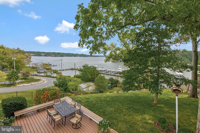 exterior space with outdoor dining area, a deck with water view, and fence