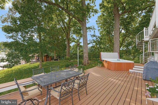 wooden deck with a yard, a hot tub, outdoor dining space, and stairs