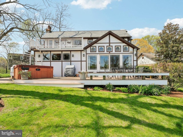 back of property with a lawn, a chimney, a hot tub, and a deck