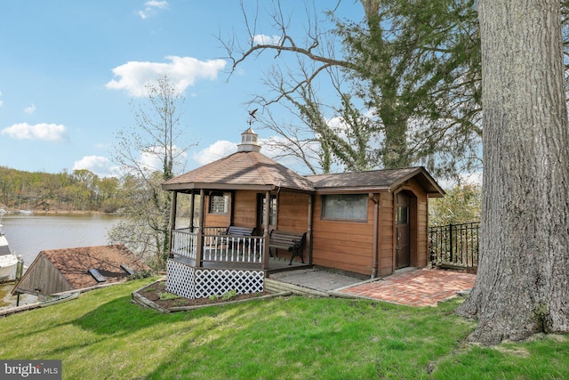 back of house with a lawn, a water view, a chimney, and a porch