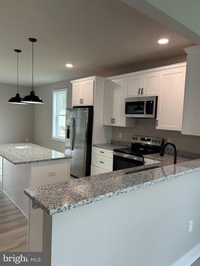 kitchen featuring a kitchen island, white cabinets, light stone countertops, appliances with stainless steel finishes, and light wood finished floors