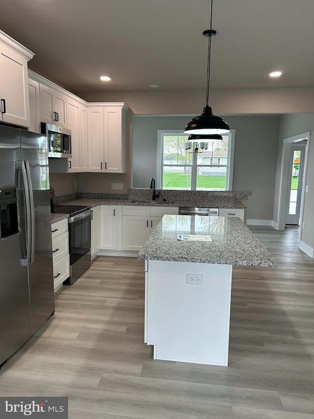 kitchen with a sink, a peninsula, recessed lighting, white cabinetry, and stainless steel appliances