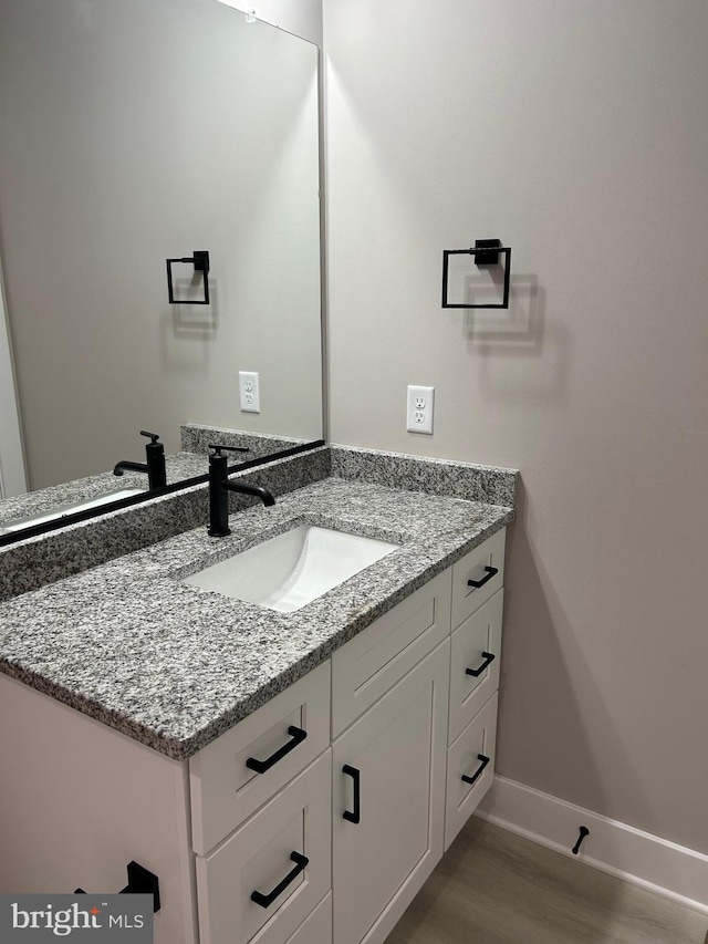 bathroom featuring vanity, baseboards, and wood finished floors