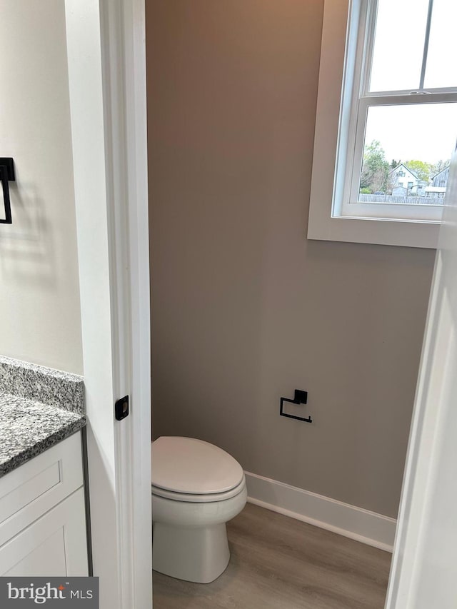 bathroom with toilet, baseboards, vanity, and wood finished floors