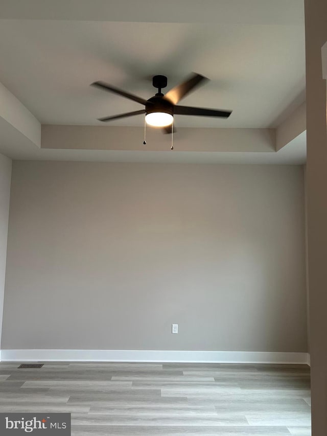spare room with light wood-type flooring, baseboards, a ceiling fan, and visible vents