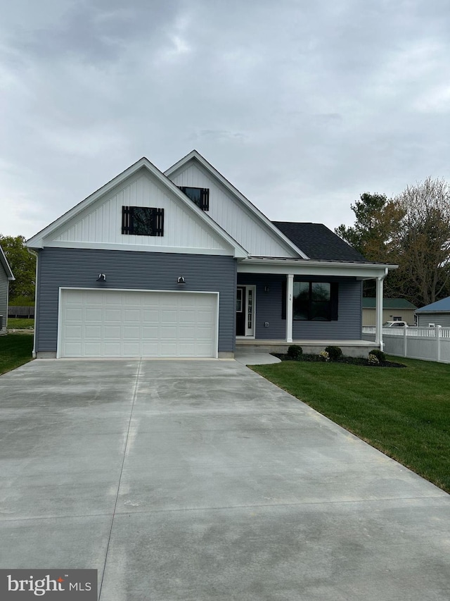 view of front of house with board and batten siding, a front yard, a garage, and concrete driveway