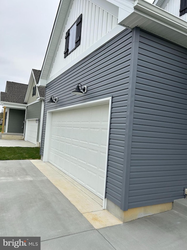 view of side of property featuring an attached garage, board and batten siding, and driveway