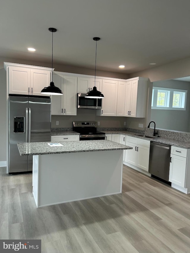 kitchen with a sink, recessed lighting, light stone counters, and stainless steel appliances