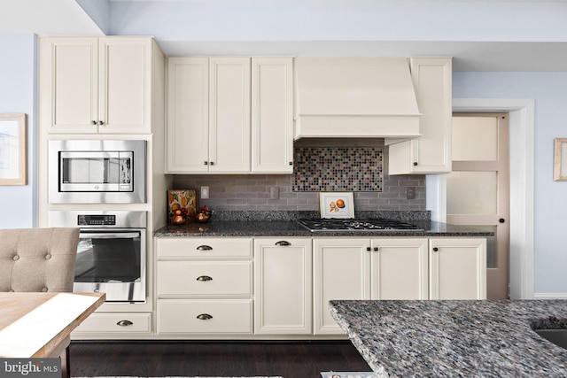 34851 Surfsong Lndg, Millville, DE 19967 - kitchen with custom exhaust hood, white cabinetry, dark stone countertops, and appliances with stainless steel finishes