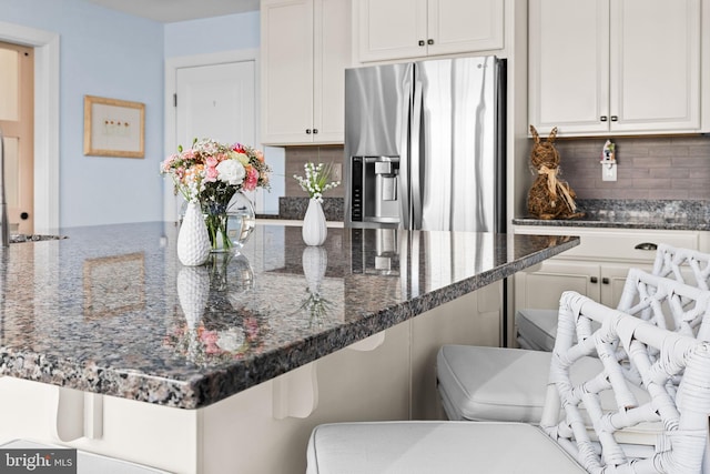 34851 Surfsong Lndg, Millville, DE 19967 - kitchen with white cabinets, dark stone countertops, stainless steel fridge with ice dispenser, a kitchen bar, and tasteful backsplash
