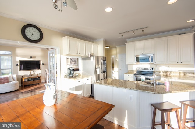 520 Bayside Dr, Stevensville, MD 21666 - kitchen featuring light stone counters, wood finished floors, a peninsula, appliances with stainless steel finishes, and white cabinetry