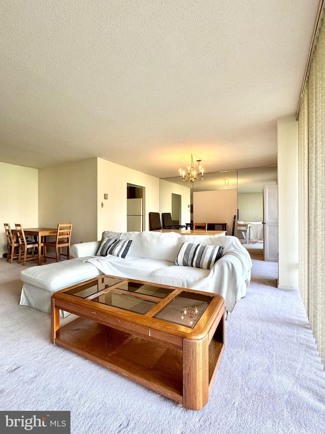 living area with an inviting chandelier, carpet floors, and a textured ceiling