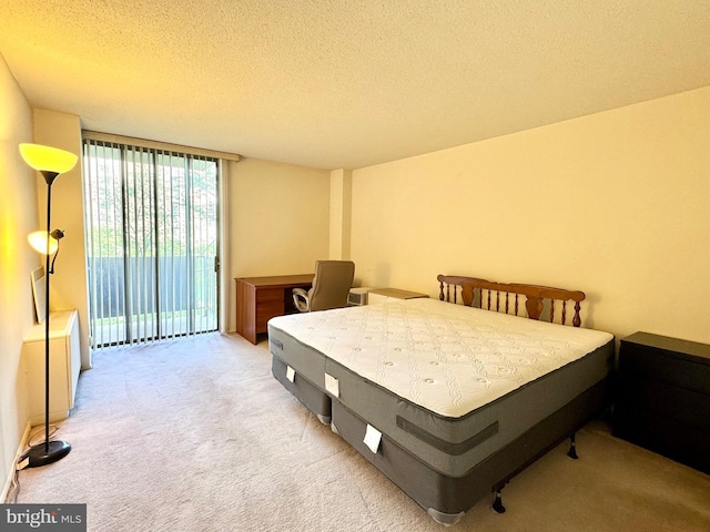 bedroom featuring access to outside, a textured ceiling, and light carpet