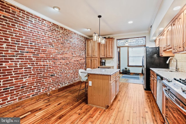 268 S E Ave, Baltimore, MD 21224 - kitchen with brick wall, a center island, stainless steel appliances, light wood-type flooring, and a breakfast bar