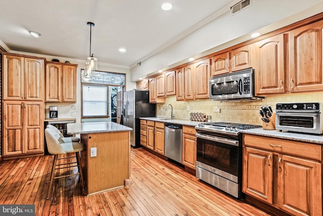 268 S E Ave, Baltimore, MD 21224 - kitchen featuring appliances with stainless steel finishes, ornamental molding, a kitchen bar, backsplash, and a kitchen island