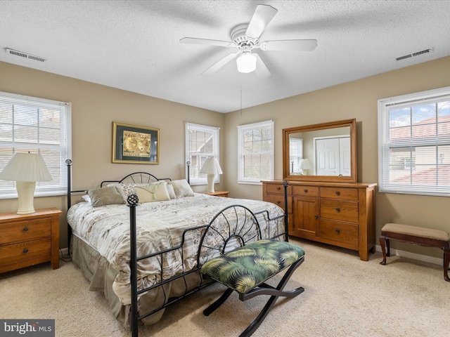 bedroom featuring visible vents, light colored carpet, and a textured ceiling