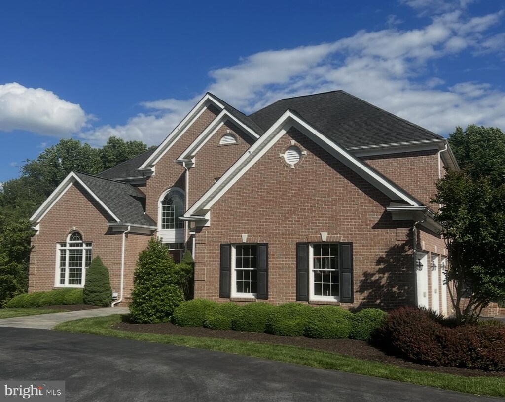 view of front of home with brick siding and roof with shingles