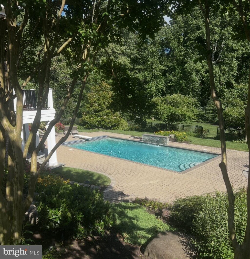 pool featuring fence, a diving board, and a patio