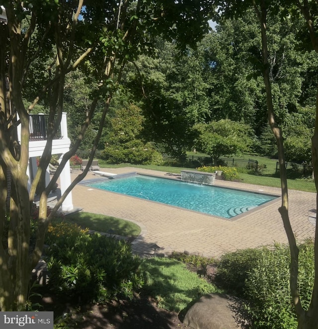 pool featuring fence, a diving board, and a patio