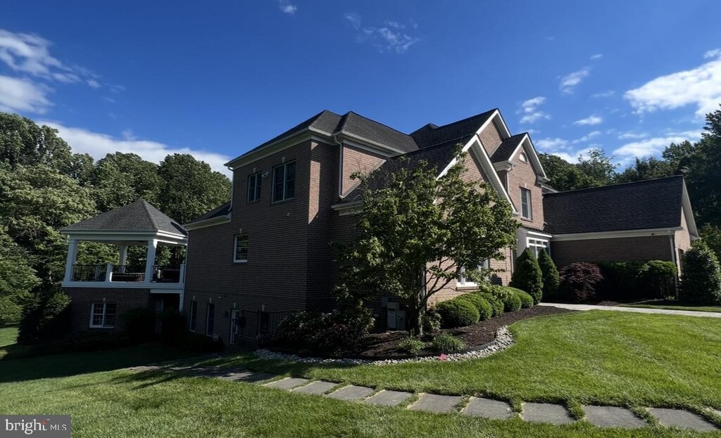 view of property exterior featuring a lawn, brick siding, and a gazebo