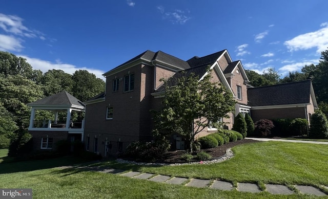 view of property exterior featuring a lawn, brick siding, and a gazebo