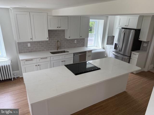 639 Old Airport Rd, Douglassville, PA 19518 - kitchen with a sink, appliances with stainless steel finishes, radiator, light wood-style flooring, and decorative backsplash